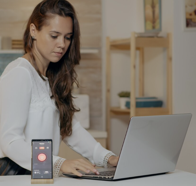 Trabajador remoto usando laptop y dispositivos digitales en su hogar.